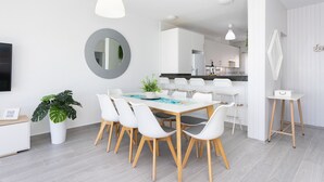 A modern dining area with a round table, white chairs, and a potted plant. - Coastal Dream with heatable pool (Güimar)