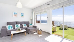 A modern living room with a grey sofa, a white coffee table, and a view of a balcony with a grassy area and a railing. - Coastal Dream with heatable pool (Güimar)