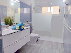 Een moderne badkamer met een wit wastafelmeubel, toilet en douchehoek.