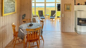 A dining area with a table and chairs, a wooden floor, and a view of the sea through large windows. - Amazing home in ørsted with kitchen (Ørsted)