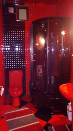 A bathroom with a red toilet, a glass-enclosed shower, and a red sink. - Family Hostel (Batumi)