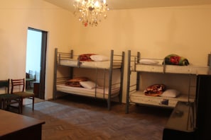 A dormitory room with bunk beds, a wooden floor, a chandelier, and a desk with a chair. - Family Hostel (Batumi)