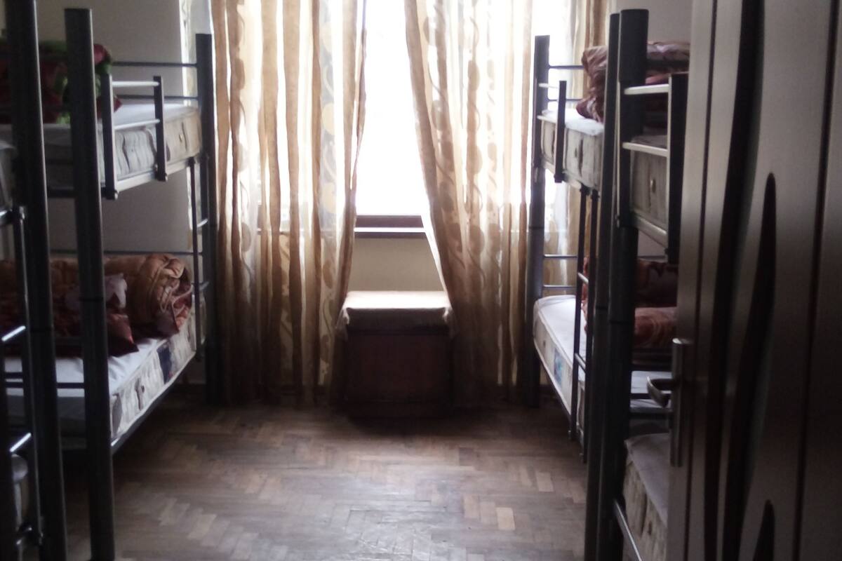 Un dormitorio con literas, suelo de madera y una ventana con cortinas.