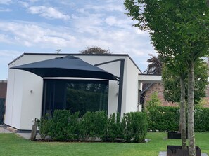 Une maison moderne dotée d’une grande baie vitrée et d’un auvent noir.