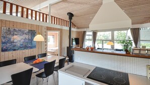 A modern kitchen with a central island, wooden ceiling, and a dining area with chairs and a table. - Awesome home in Ebeltoft with sauna (Ebeltoft)