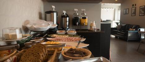 A buffet setup with various food items and beverages, including bread, cheese, and a coffee station.