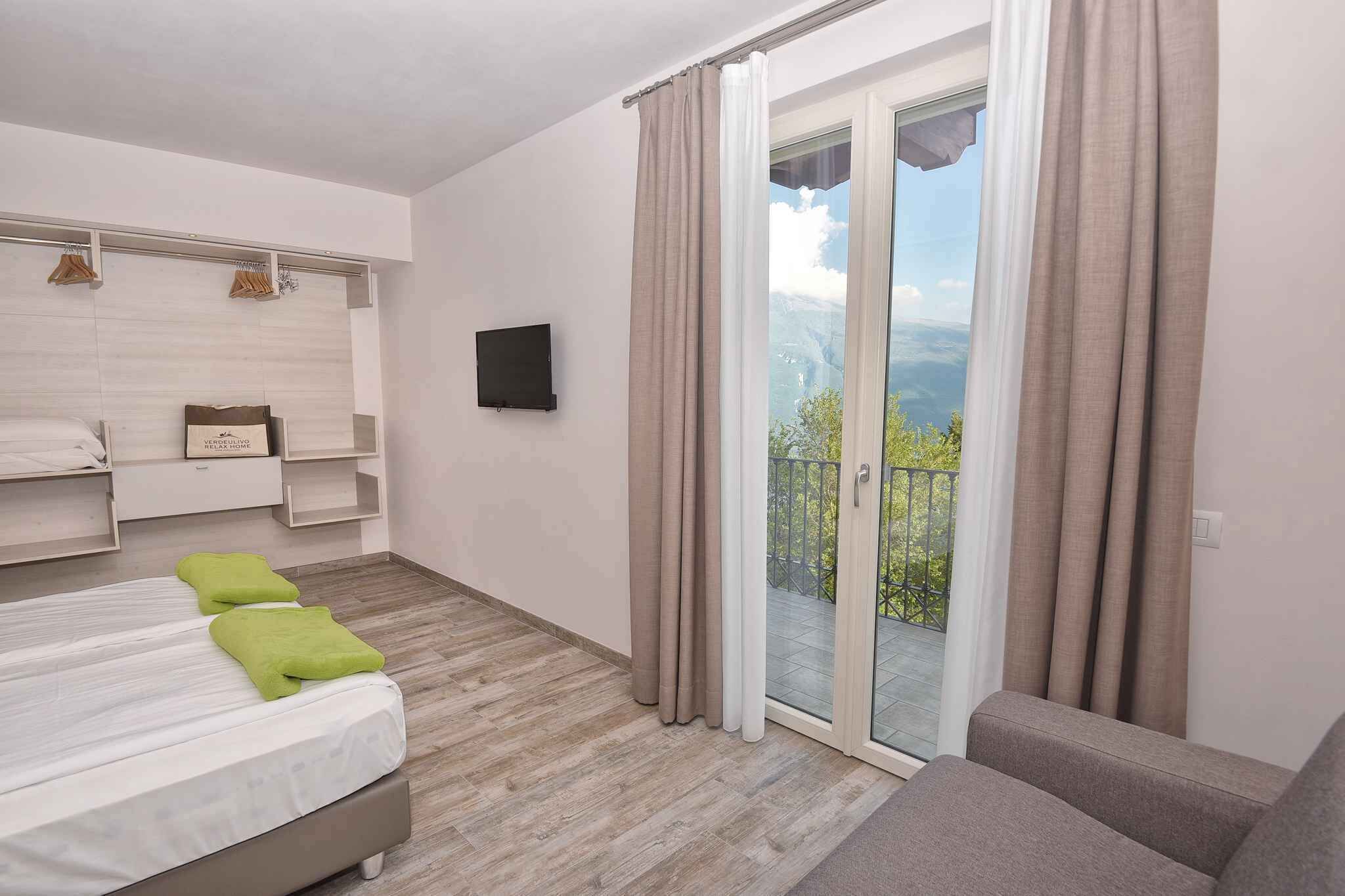 Une chambre moderne avec un lit, un canapé, une télévision et un balcon agrémenté de rideaux.