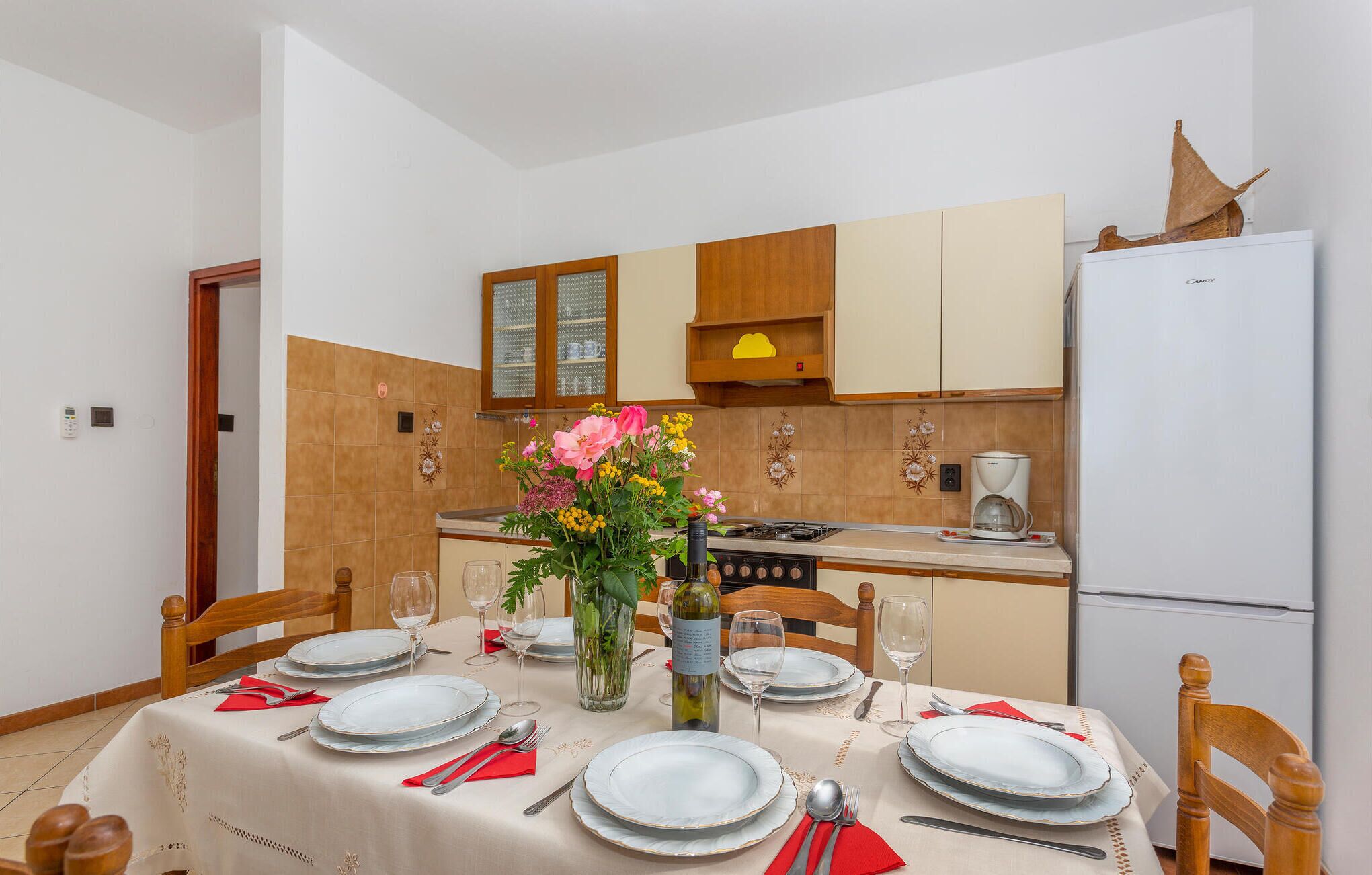 A dining area with a table set for four, a stove, and a refrigerator.