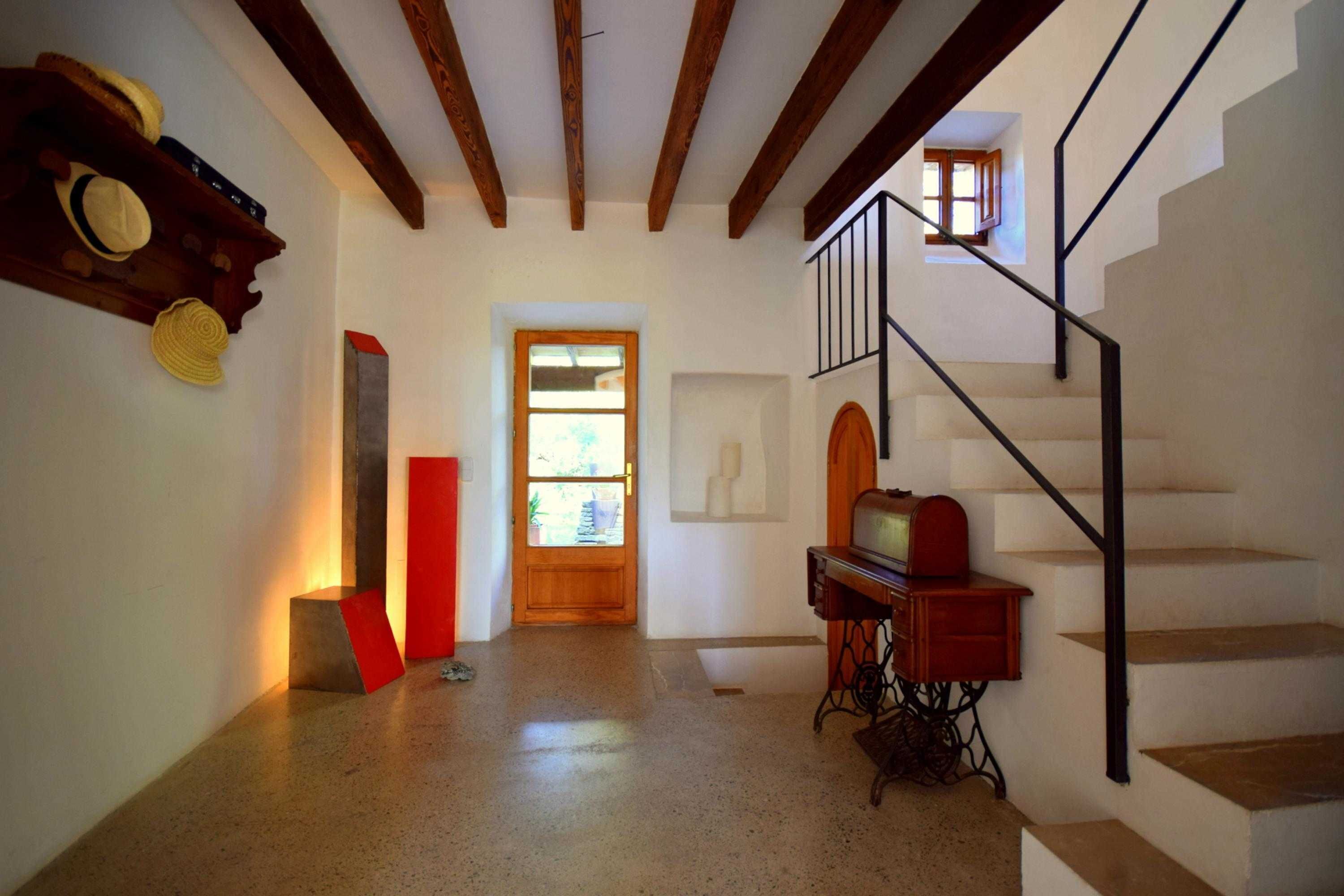 Una escalera con detalles de madera y barandilla metálica, que conduce a una plataforma con una puerta de madera y un ventanal.
