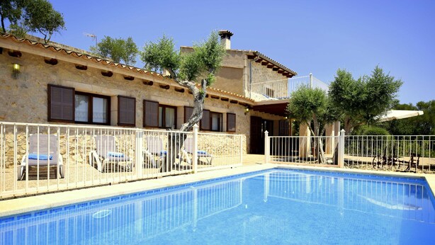 A swimming pool with lounge chairs and a stone building with windows. - 750139 Sa Font near Petra (license ETV/941) - 750139 Sa Font (Petra)