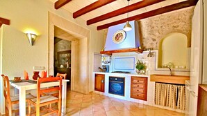 A kitchen with a dining table and chairs, an oven, a microwave, and a sink. - 750139 Sa Font near Petra (license ETV/941) - 750139 Sa Font (Petra)