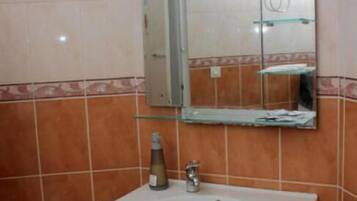 A bathroom with a white sink, a mirror above it, and a bottle of hand soap on the counter.