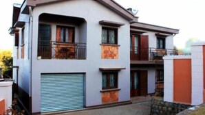 A two-story residential building with a garage, balconies, and a stone foundation. - Manaona Guest House (Antananarivo)
