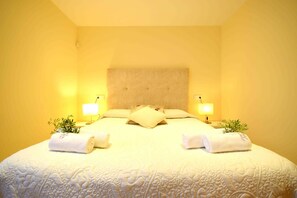 A hotel room with a large bed, two bedside lamps, and a headboard.