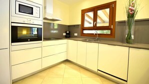 A modern kitchen with built-in appliances, a window, and a vase with flowers. - 44236 Modern beach house Es Baladre (Alcúdia)