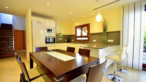 A modern kitchen with a dining area, a built-in oven, and a large window. - 44236 Modern beach house Es Baladre (Alcúdia)
