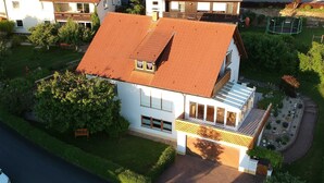 A two-story house with a red-tiled roof, a balcony, and a garden with a small pond. - Apartment on the Rotdornweg (Heiligenstadt i.OFr.)