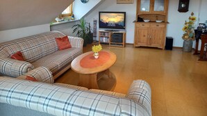 A cozy living room with a plaid sofa, a wooden coffee table, and a television on a stand. - Apartment on the Rotdornweg (Heiligenstadt i.OFr.)