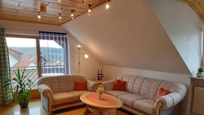 A cozy living room with a checkered sofa, a small round table with a vase, and a potted plant. - Apartment on the Rotdornweg (Heiligenstadt i.OFr.)