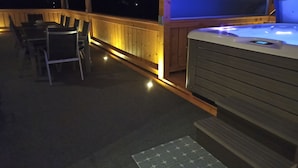 Ett trädäck med ett bubbelbad och ett bord med stolar.