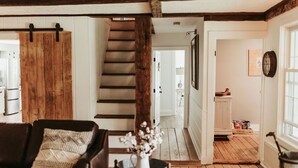 A cozy living room with a leather sofa, a wooden coffee table, and a staircase leading to another room.
