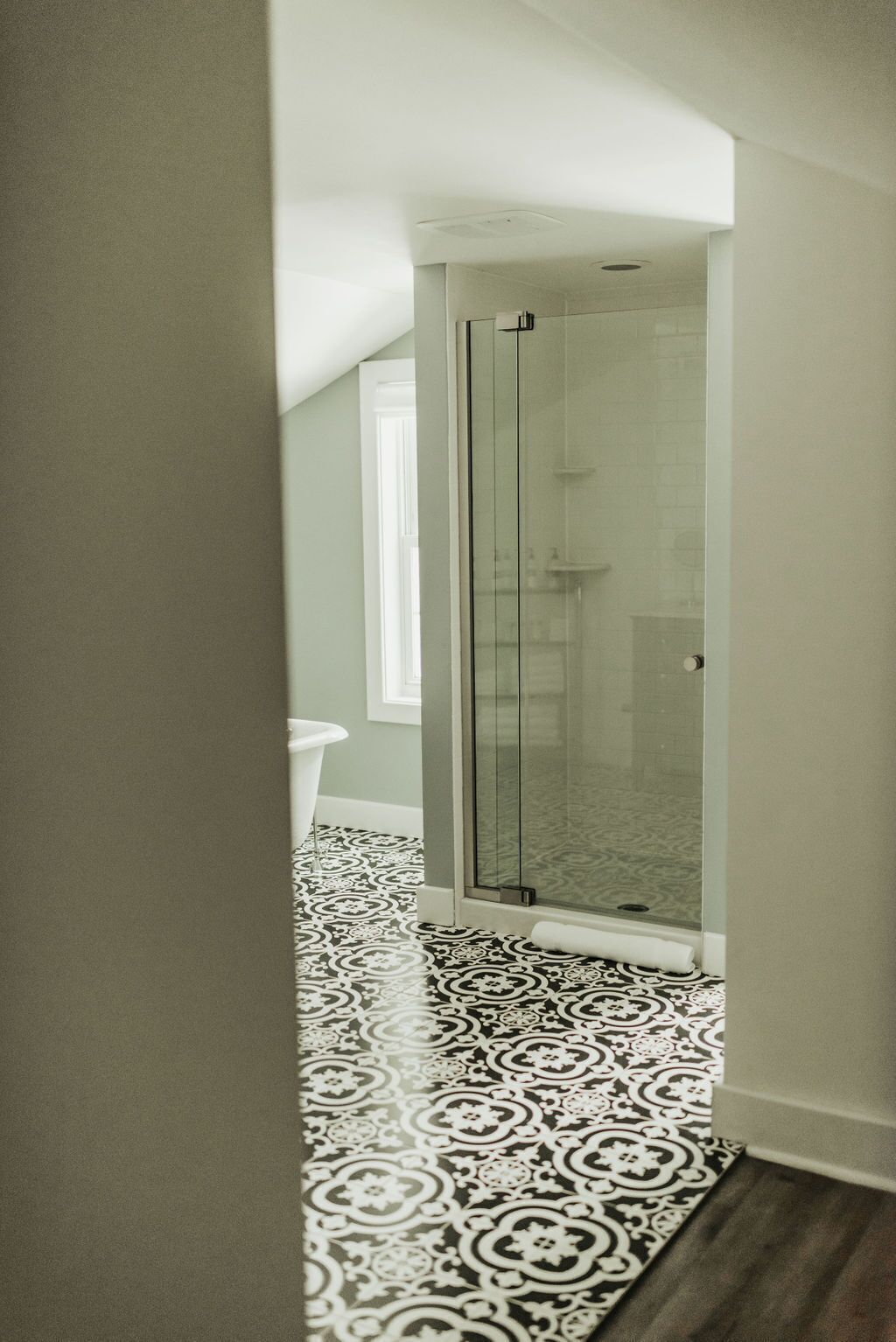 A modern bathroom with a glass shower enclosure, a patterned floor, and a white toilet.