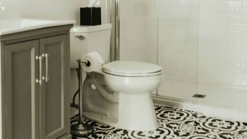 A bathroom with a toilet, a shower, and a sink.
