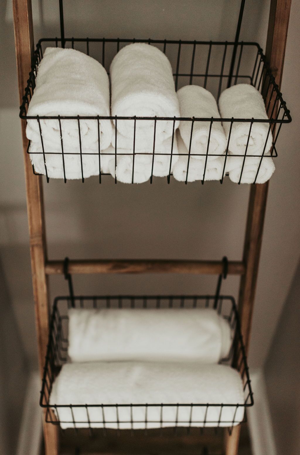 A metal rack with three shelves holding rolled white towels.