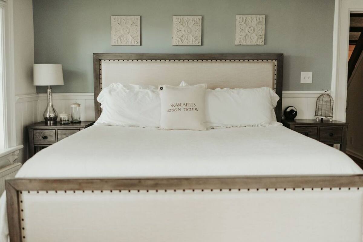 A neatly made bed with a headboard, a bedside table with a lamp, and decorative wall pieces.