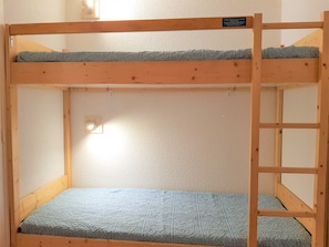 Uma cama beliche com estrutura de madeira e um colchão.