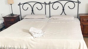 A neatly made bed with a folded white towel, a wooden nightstand with a lamp, and a dresser. - Stunning apartment in Los Alcazares with WiFi (Los Alcazares)