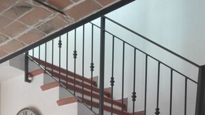 A wooden staircase with a metal railing, a wall clock, and a calendar hanging on the wall.