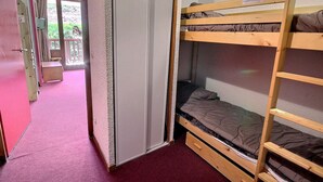 Habitación con literas y una puerta que da a un balcón.