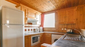 A kitchen with wooden cabinets, a refrigerator, a microwave, a coffee maker, a toaster, and a washing machine. - Studio Cabin Arc 1600, 5 Persons, Ski-in/Ski-out, WiFi (Les Arcs 1600)