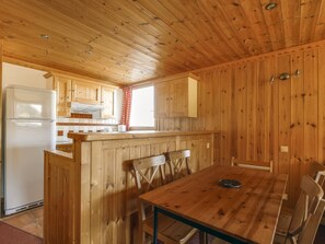 Compact kitchen with a dining area, featuring a refrigerator, wooden countertop, and a dining table with four chairs.