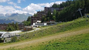 A hotel with multiple floors, a ski lift, and a mountainous backdrop. - Cozy studio Arc 1600, ski-in/ski-out, perfect for 2, WiFi included (Les Arcs 1600)