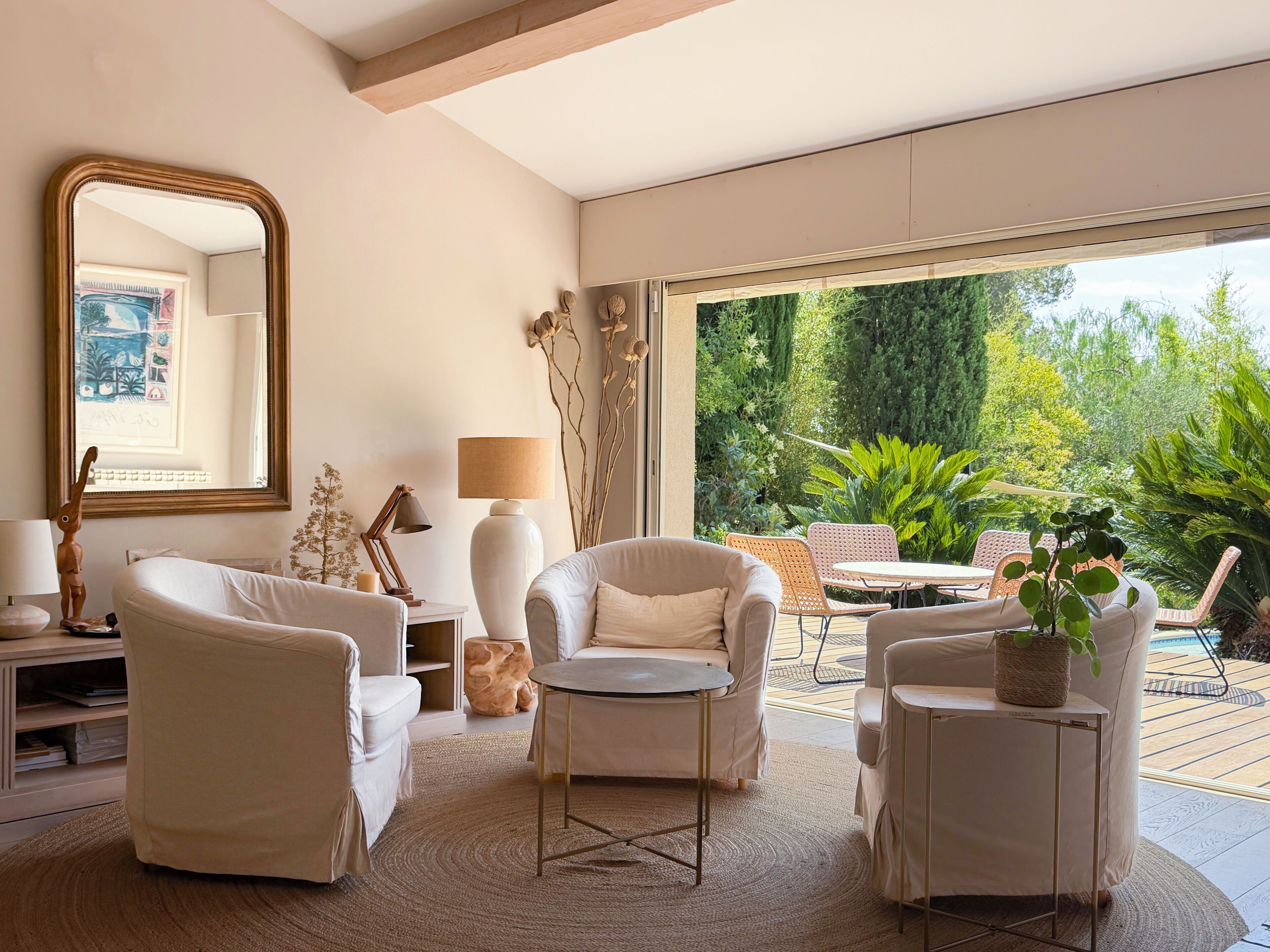 A modern living room with a large mirror, a round table, and two armchairs.