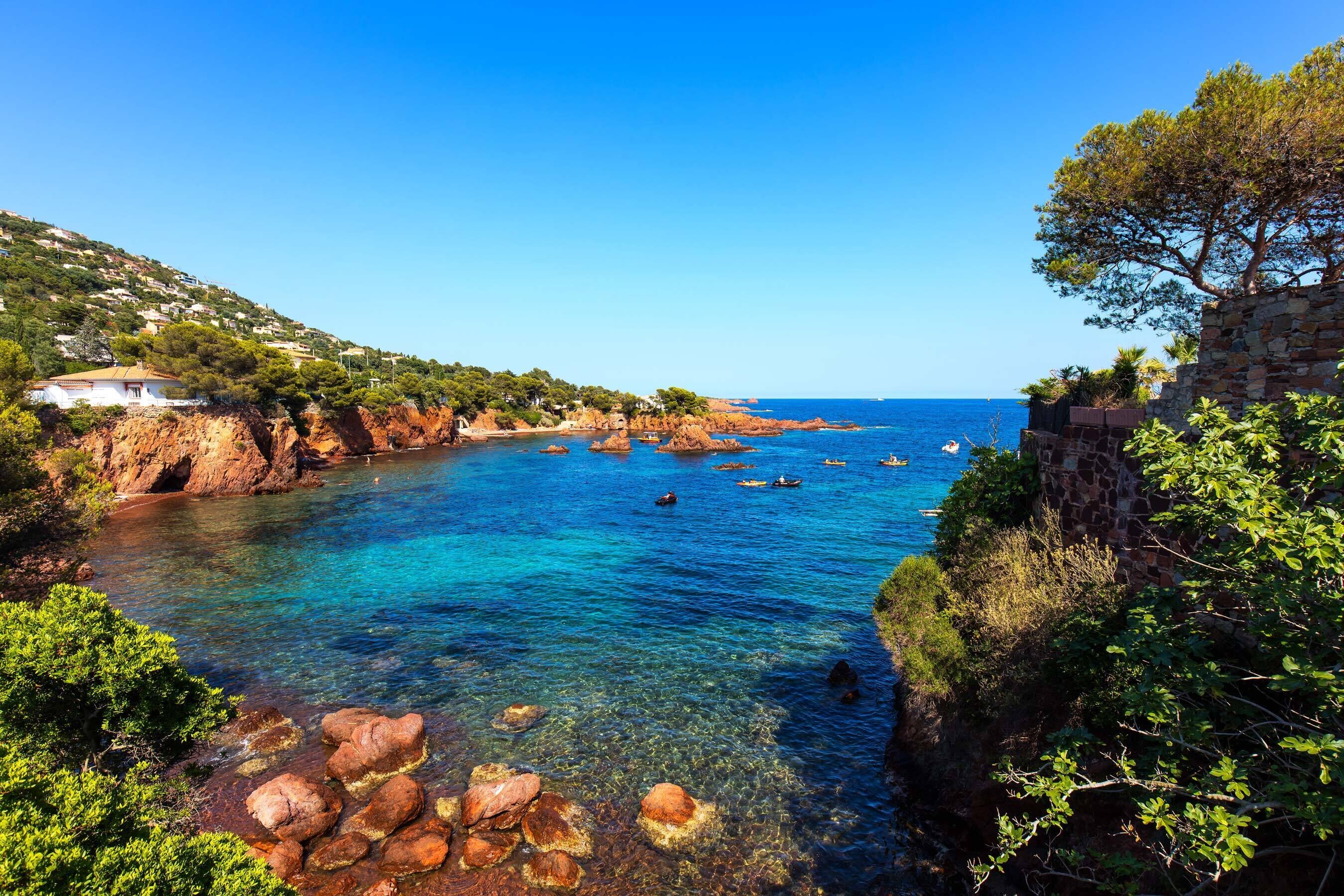 Eine Küstenlandschaft mit klarem, blauem Wasser, felsigen Klippen und viel Grün.