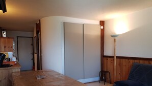 Une pièce avec une table en bois, un canapé bleu, un meuble en bois et une porte coulissante.