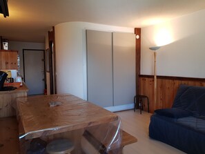 Een kamer met een houten tafel, een blauwe bank, een houten kast en een schuifdeur.