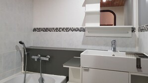 Une salle de bain avec une baignoire, un lavabo et un miroir.