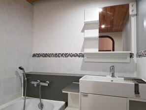 Een badkamer met een bad, een wastafel en een spiegel.