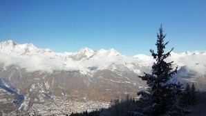Un paysage de montagne avec des sommets enneigés et une ville en contrebas.