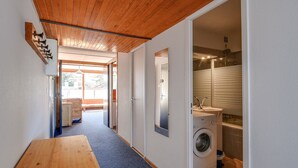 Un couloir avec un banc en bois, un lave-linge et un évier dans une petite pièce.