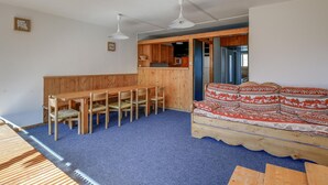 Un espace de vie compact comprenant un coin repas, un canapé et une kitchenette.