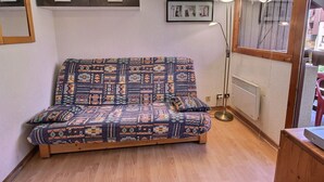 A small, cozy room with a patterned sofa, a floor lamp, and a framed picture on the wall. - Cozy studio for 4 in Vallandry, close to slopes (Peisey-Vallandry)