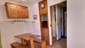 A wooden dining table with benches, a wooden cabinet above, and a clock on the wall. - Cozy studio for 4 in Vallandry, close to slopes (Peisey-Vallandry)