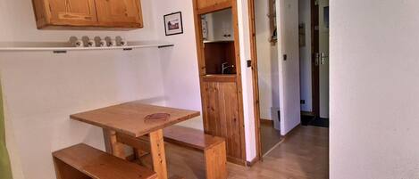 A wooden dining table with benches, a wooden cabinet above, and a clock on the wall.