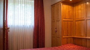 A bedroom with a bed, a wardrobe, and a window with curtains. - Homerez - Apt in Oderen with mountain view (Oderen)