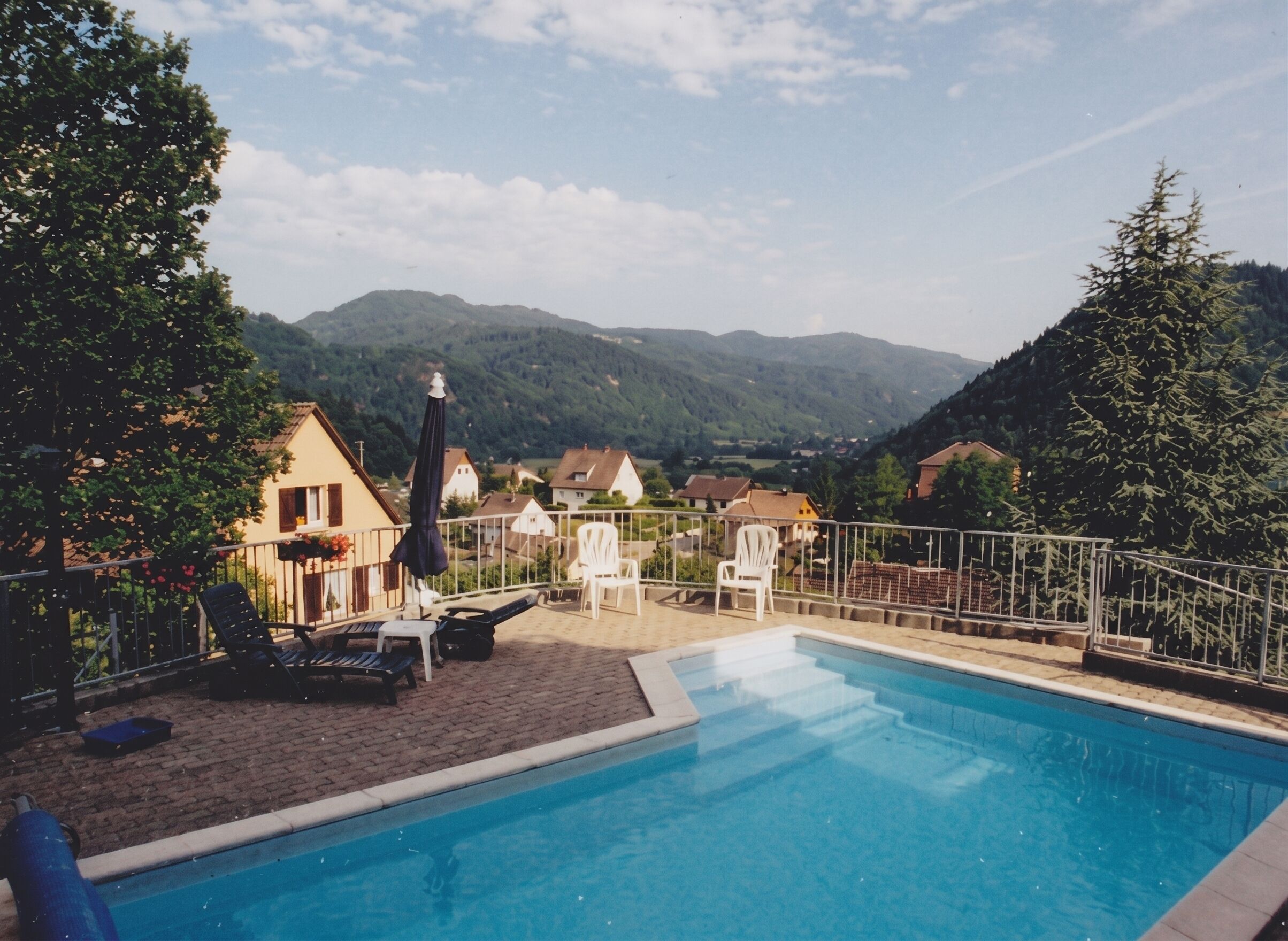 Une piscine dotée de chaises longues et offrant une vue sur un village et des montagnes.